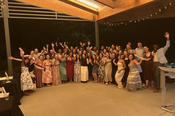 A group photo of the residency program under a pavilion, smiling and raising their arms.