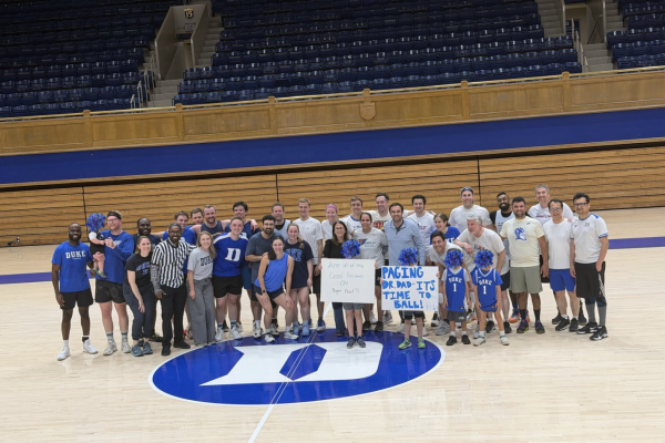 Group photo of residency program standing on the center of Cameron Indoor Stadium.