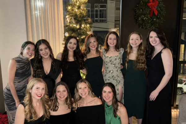 Residents dressed in elegant outfits at the annual holiday party, smiling and posing for a group picture. 
