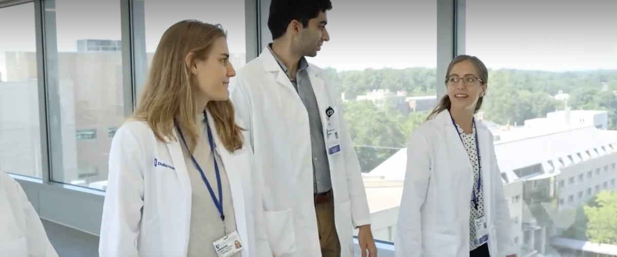 IM residents wearing white coats walking down a hallway. 