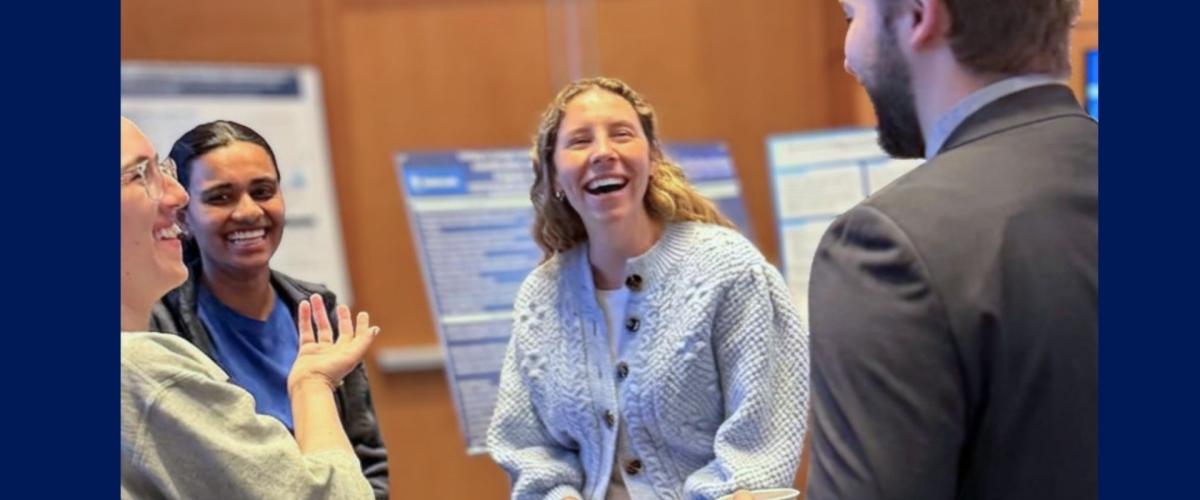 A group of residents smiling and talking in a poster presentation setting.