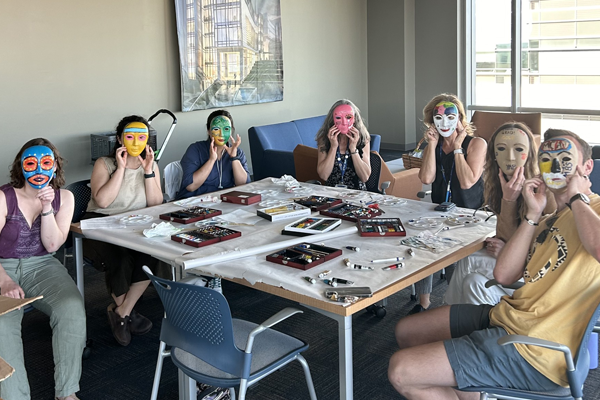 Students around a table with masks made during a crafting activity